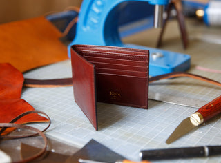 Brown leather wallet on a workbench with tools in the background